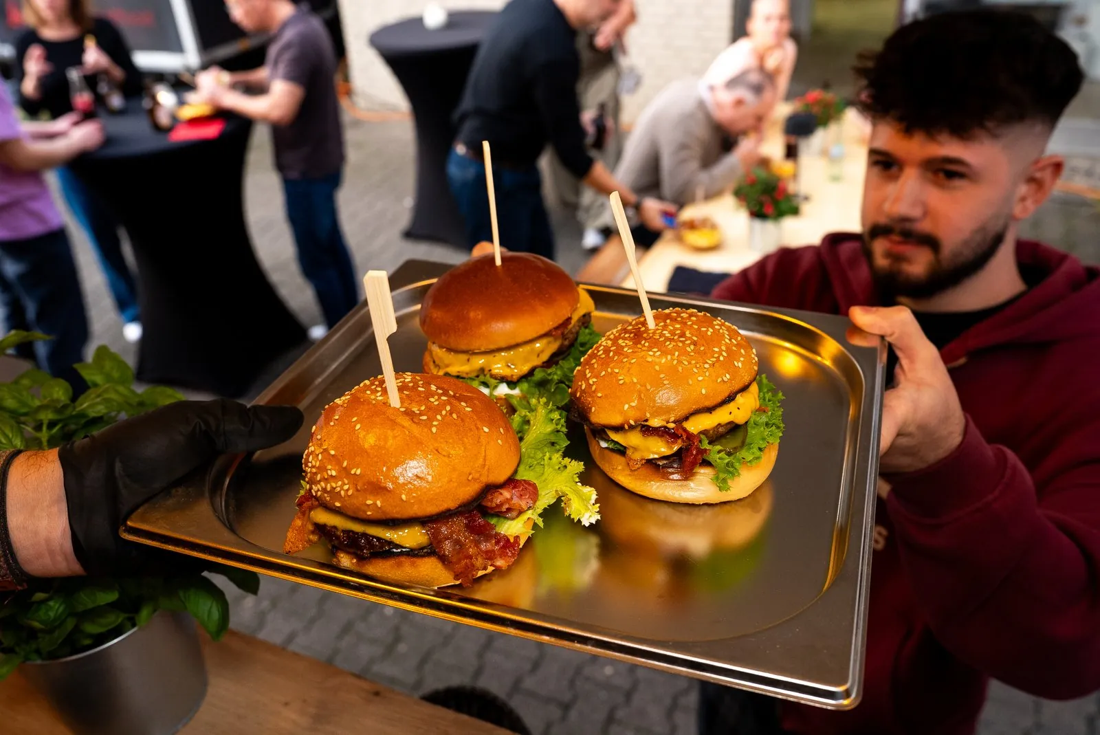 Drei Burger mit Cheddar und Bacon auf einem Tablett bei der Ausgabe