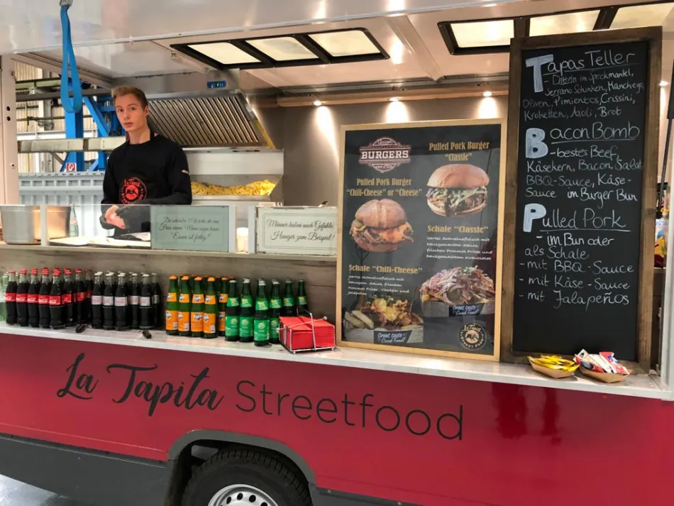 Theke des roten La Tapita Foodtrucks mit Menütafeln und Getränken