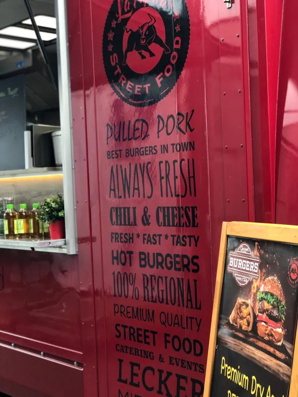 Seitenwand des roten La Tapita Foodtrucks mit Branding und Menü
