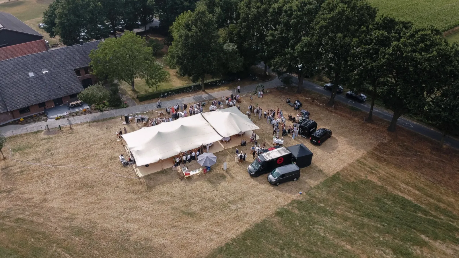 Drohnenaufnahme von Zelt und La Tapita Foodtruck auf der Wiese bei einer Hochzeit