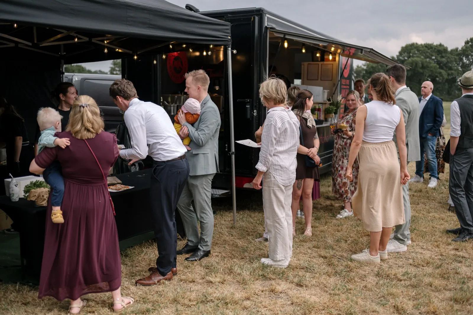 Hochzeitsgäste stehen am La Tapita Foodtruck auf einer Wiese an