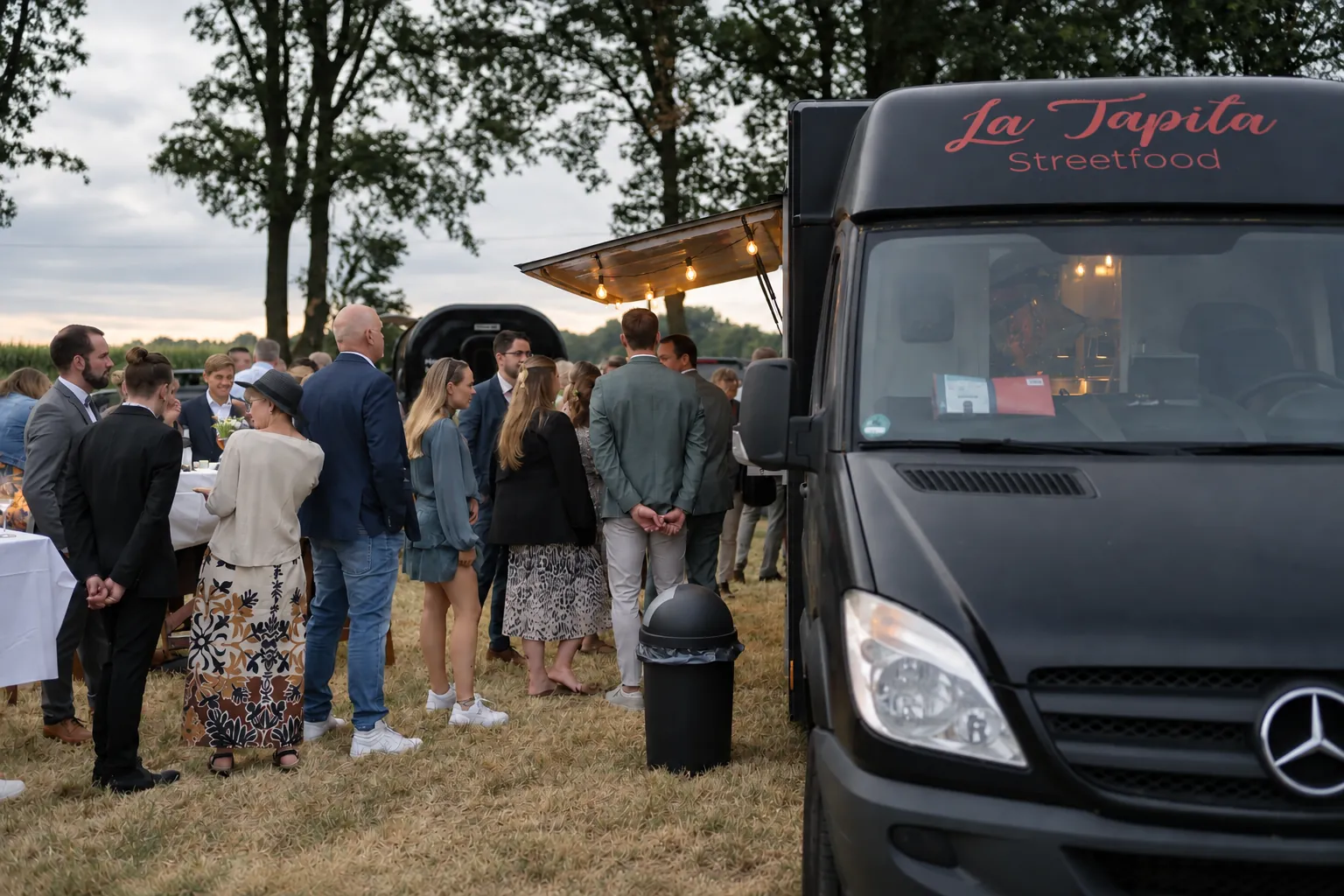 Hochzeitsgäste auf der Wiese am schwarzen La Tapita Foodtruck