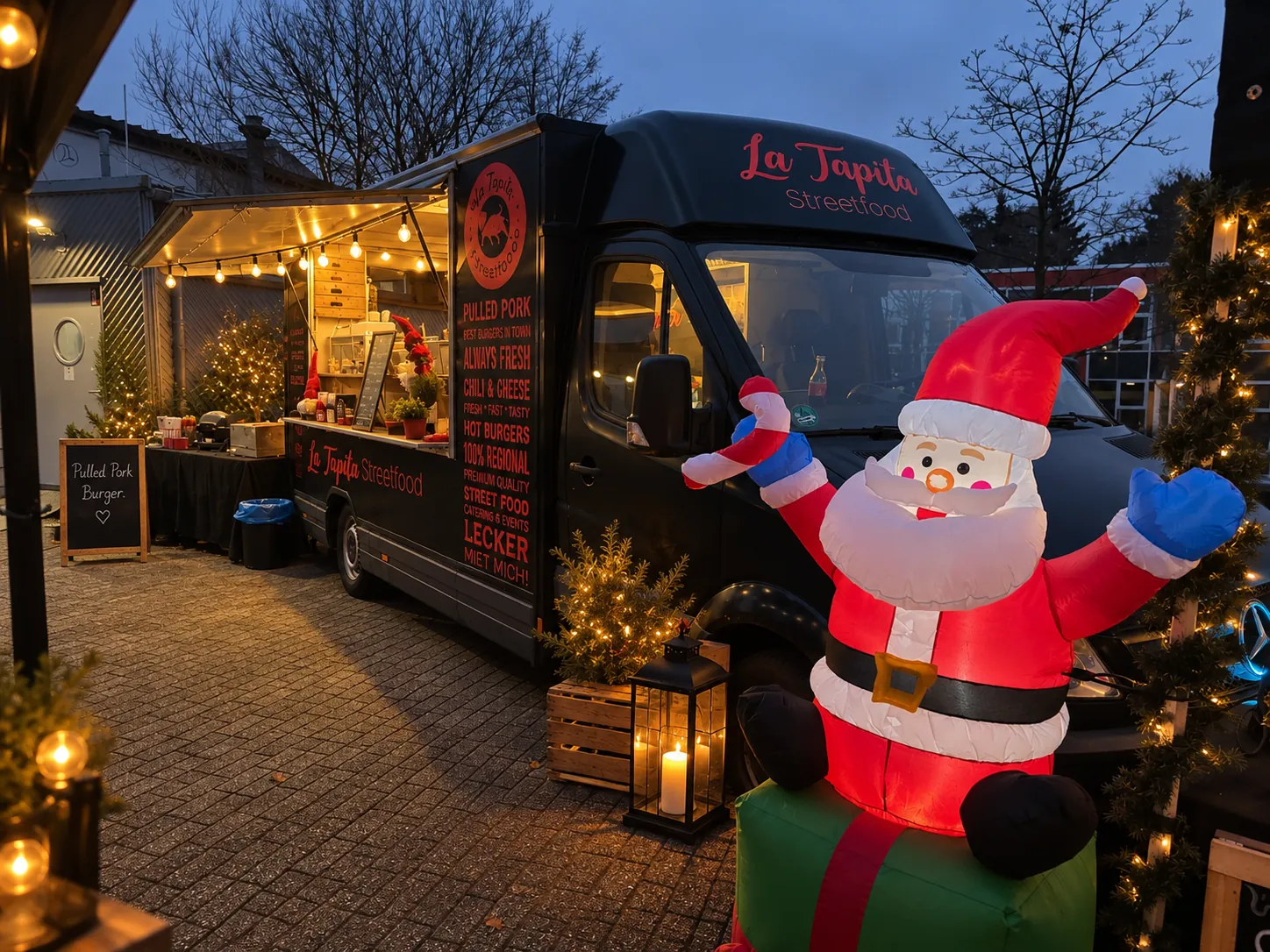 Schwarzer La Tapita Foodtruck mit Weihnachtsmann-Deko am Abend