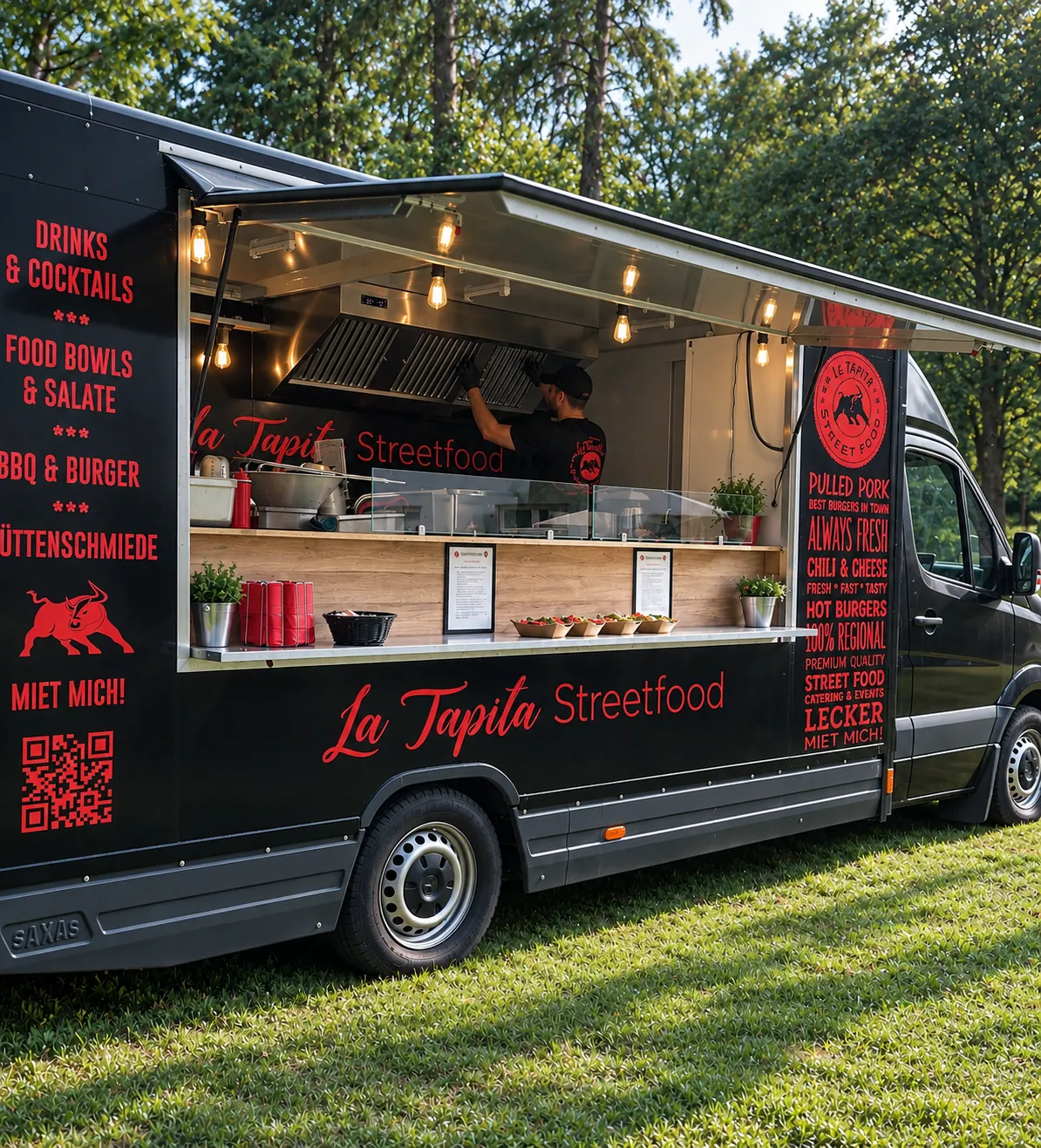 Schwarzer La Tapita Foodtruck mit geöffneter Theke auf einer Wiese