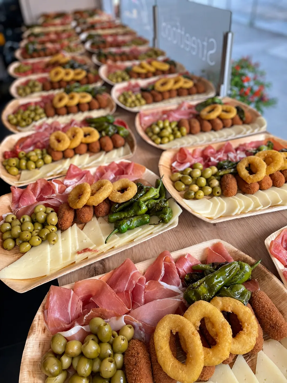Reihe angerichteter Tapas-Teller mit Calamares, Serrano und Oliven