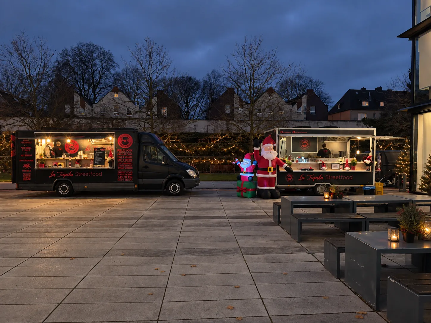 Zwei weihnachtlich beleuchtete La Tapita Foodtrucks in der Dämmerung